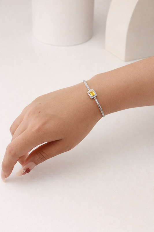 Hand wearing a bracelet with a yellow gemstone on a white background