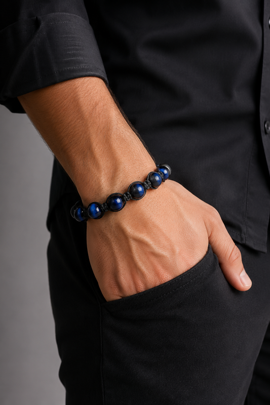 Person wearing a black and blue beaded bracelet on a plain background