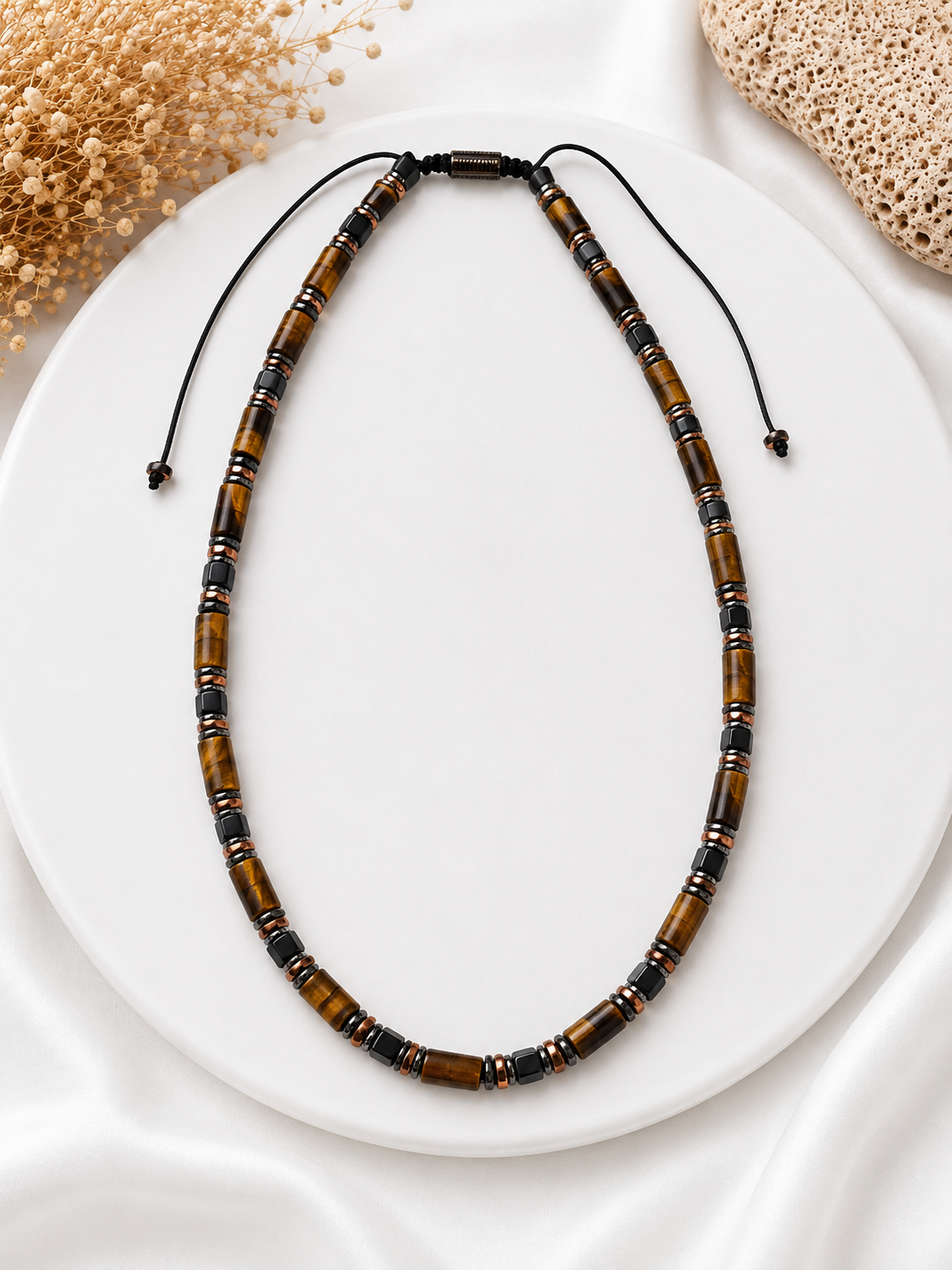 Beaded necklace with brown and black beads on a white plate