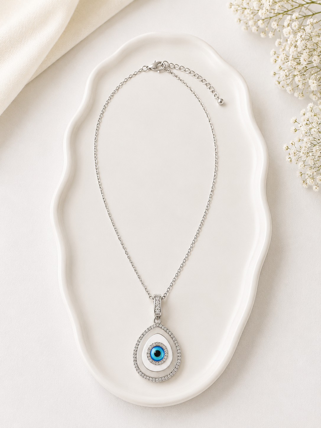 Necklace with an eye-shaped pendant on a white dish