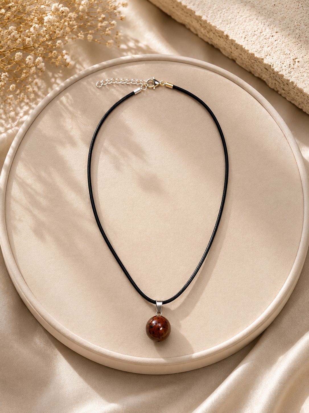 Necklace with a brown pendant on a beige plate