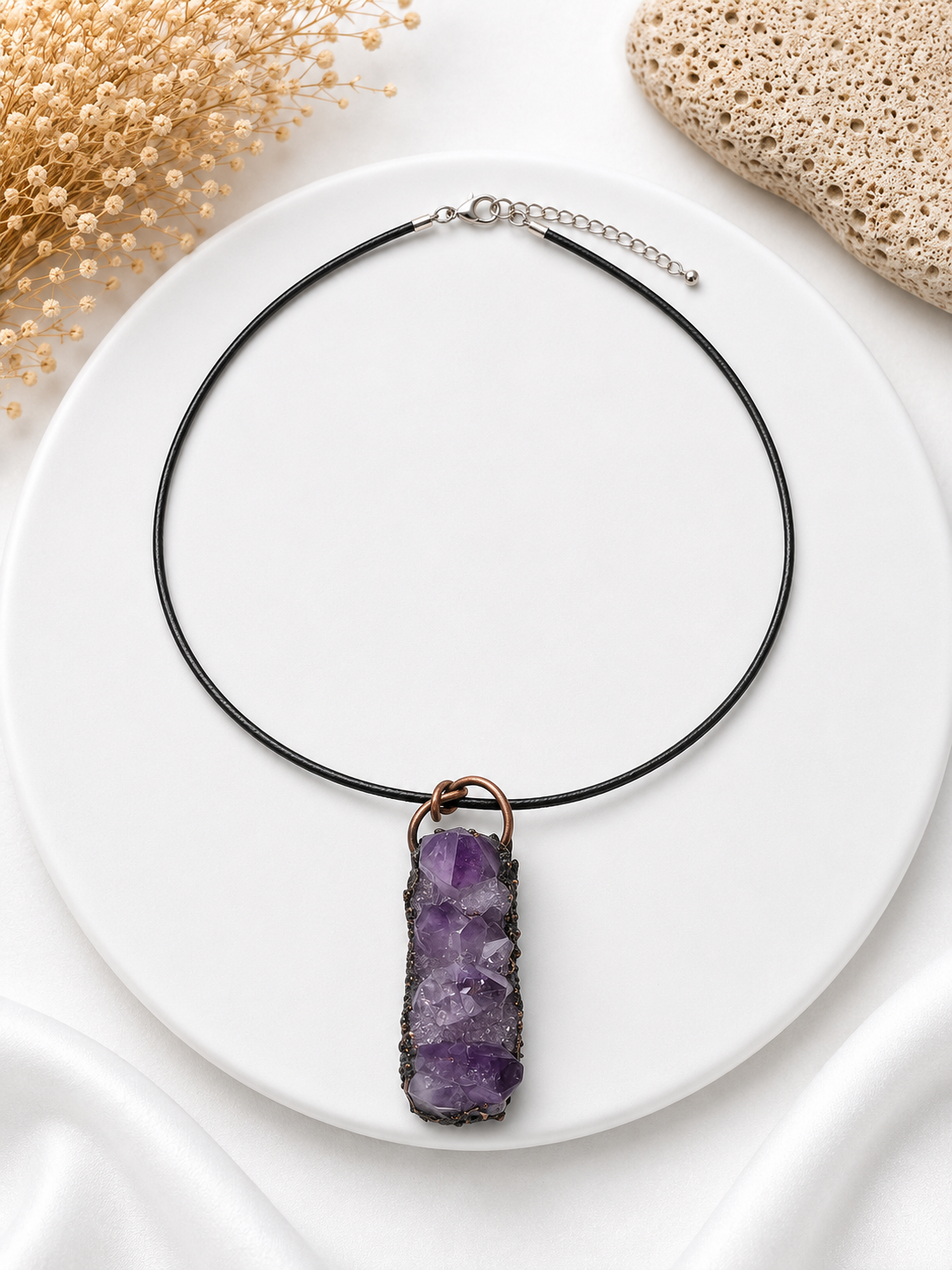 Necklace with a purple crystal pendant on a white plate
