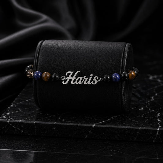 Bracelet with 'Haris' engraving on a black leather case against a dark background