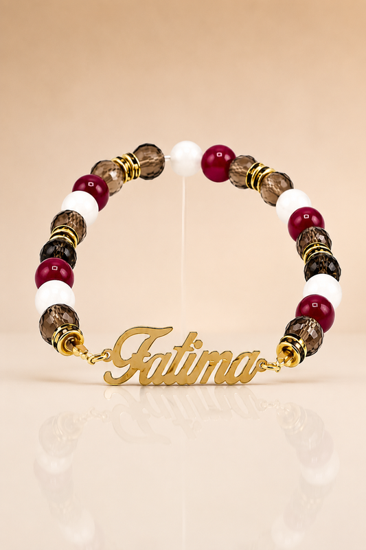 Bracelet with beads and gold nameplate 'Fatima' on a beige background