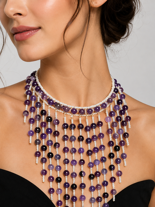 Woman wearing a beaded necklace with purple and black beads on a neutral background