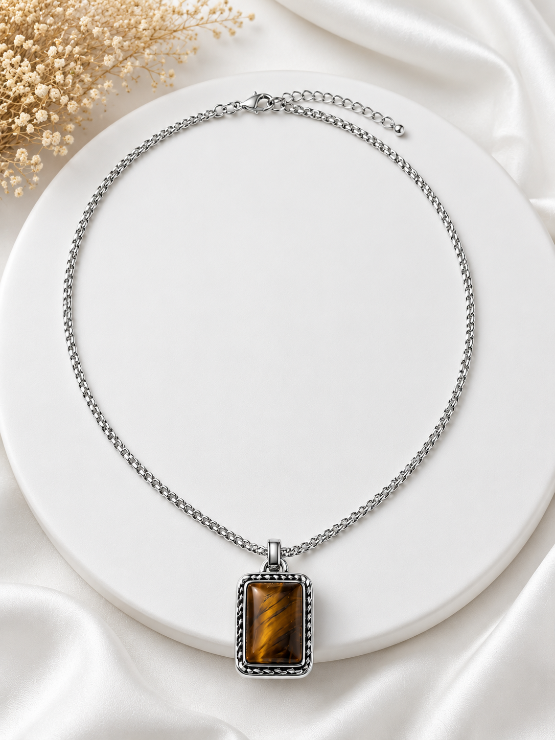 Silver necklace with a rectangular pendant on a white surface