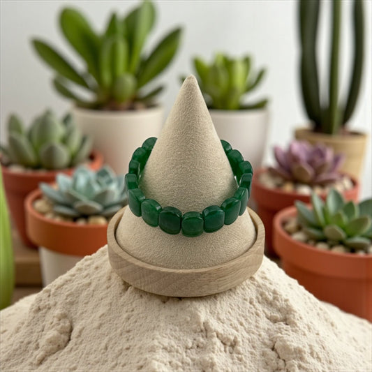 Green bracelet on a sand sculpture with potted plants in the background