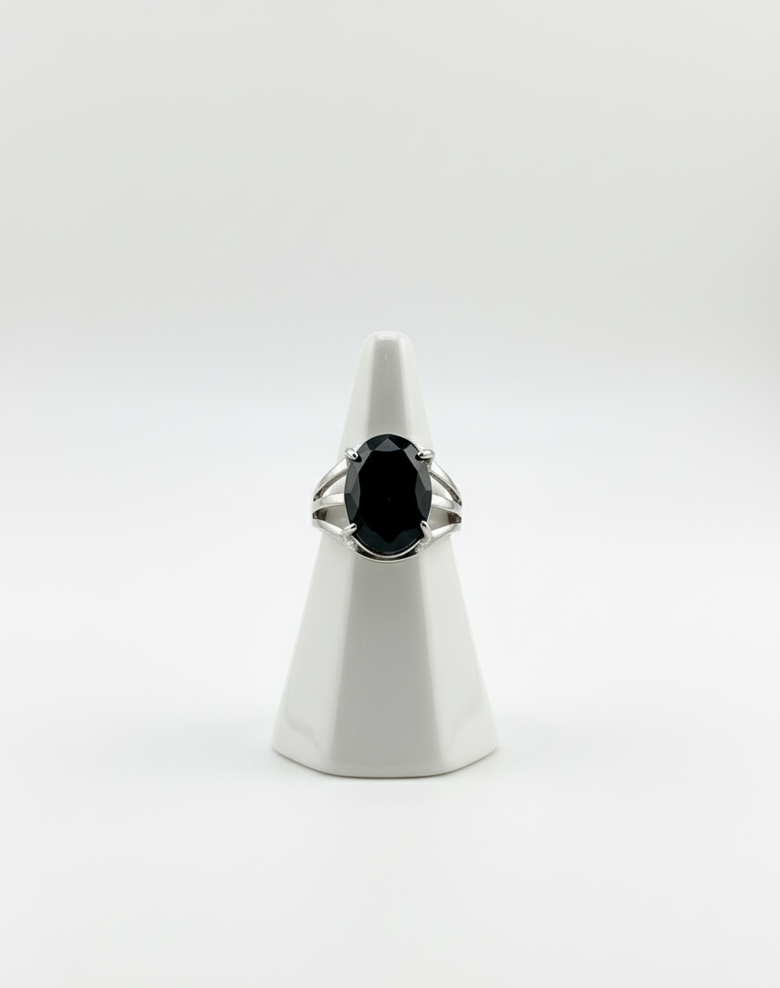 Ring with a black gemstone on a white stand against a white background