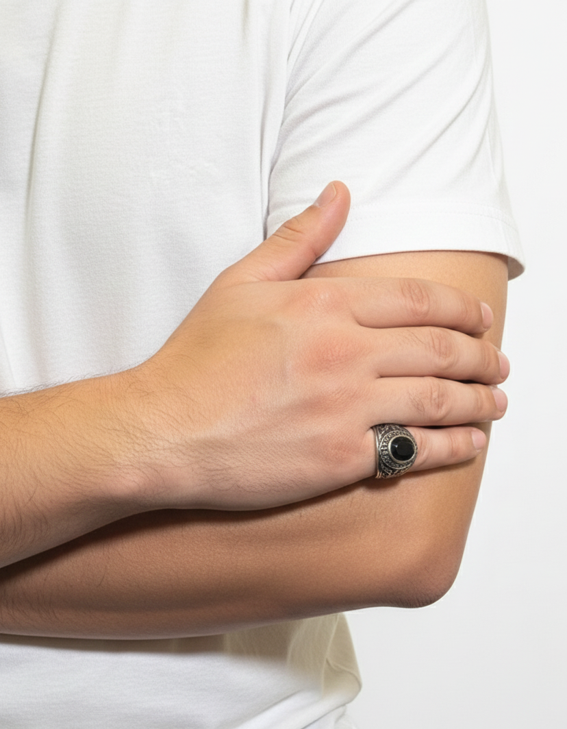 Hand wearing a ring with a black stone on a white background