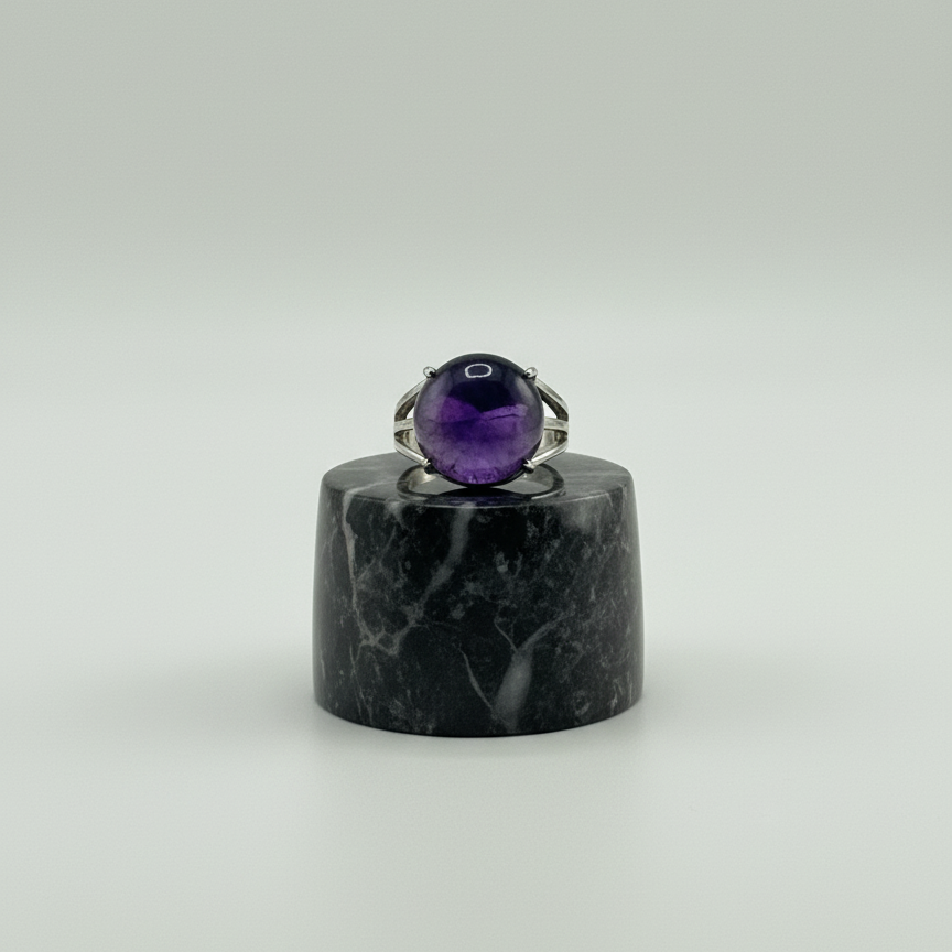 Amethyst ring on a black marble stand against a white background