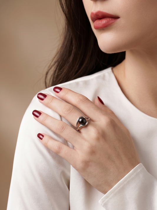 A close-up lifestyle shot of a woman wearing a silver ring with a dark oval stone, resting her hand on her shoulder.