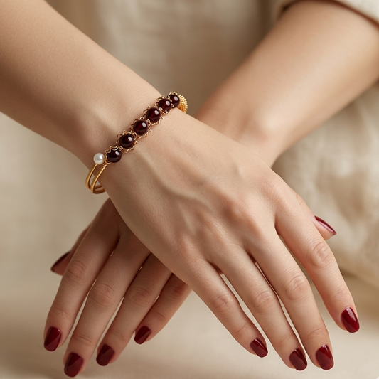 Close-up of a hand wearing a bracelet with red beads on a neutral background