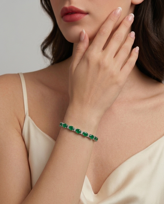 Woman wearing a green emerald bracelet on a neutral background