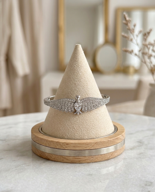 Silver bracelet on a cone-shaped jewelry stand with a wooden base.