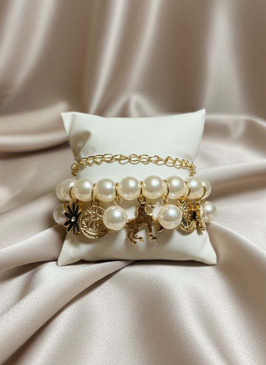 Gold and pearl bracelet on a white pillow with a beige background