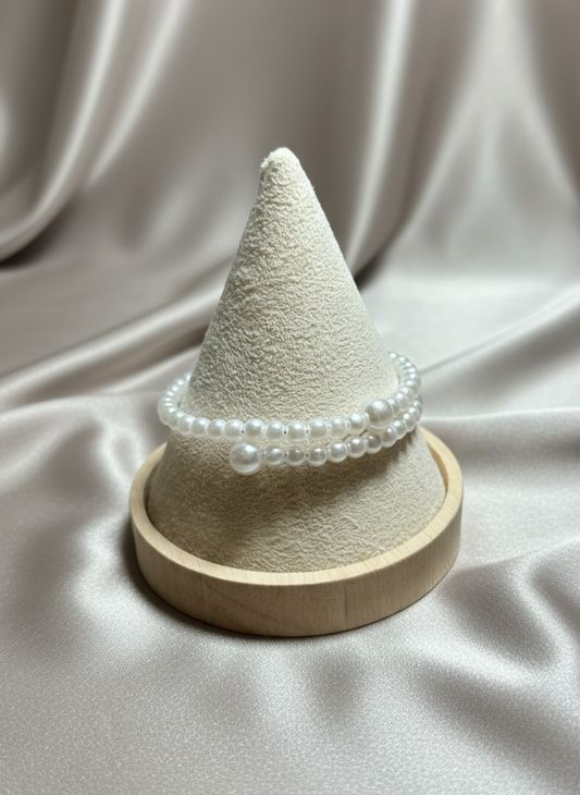 Textured cone-shaped object with pearl-like beads on a beige fabric background