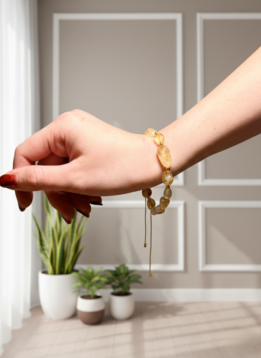 Hand wearing a beaded bracelet with a neutral background and plants