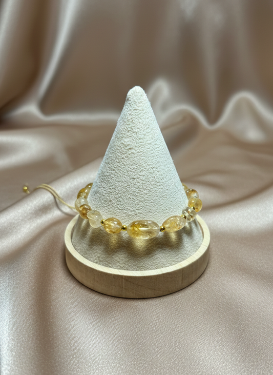 White cone-shaped jewelry display with yellow beads on a beige fabric background
