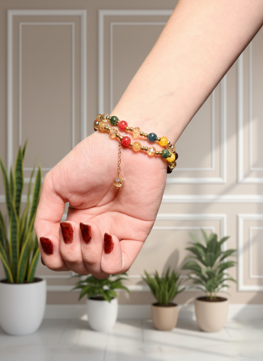 Hand wearing a colorful beaded bracelet with plants in the background