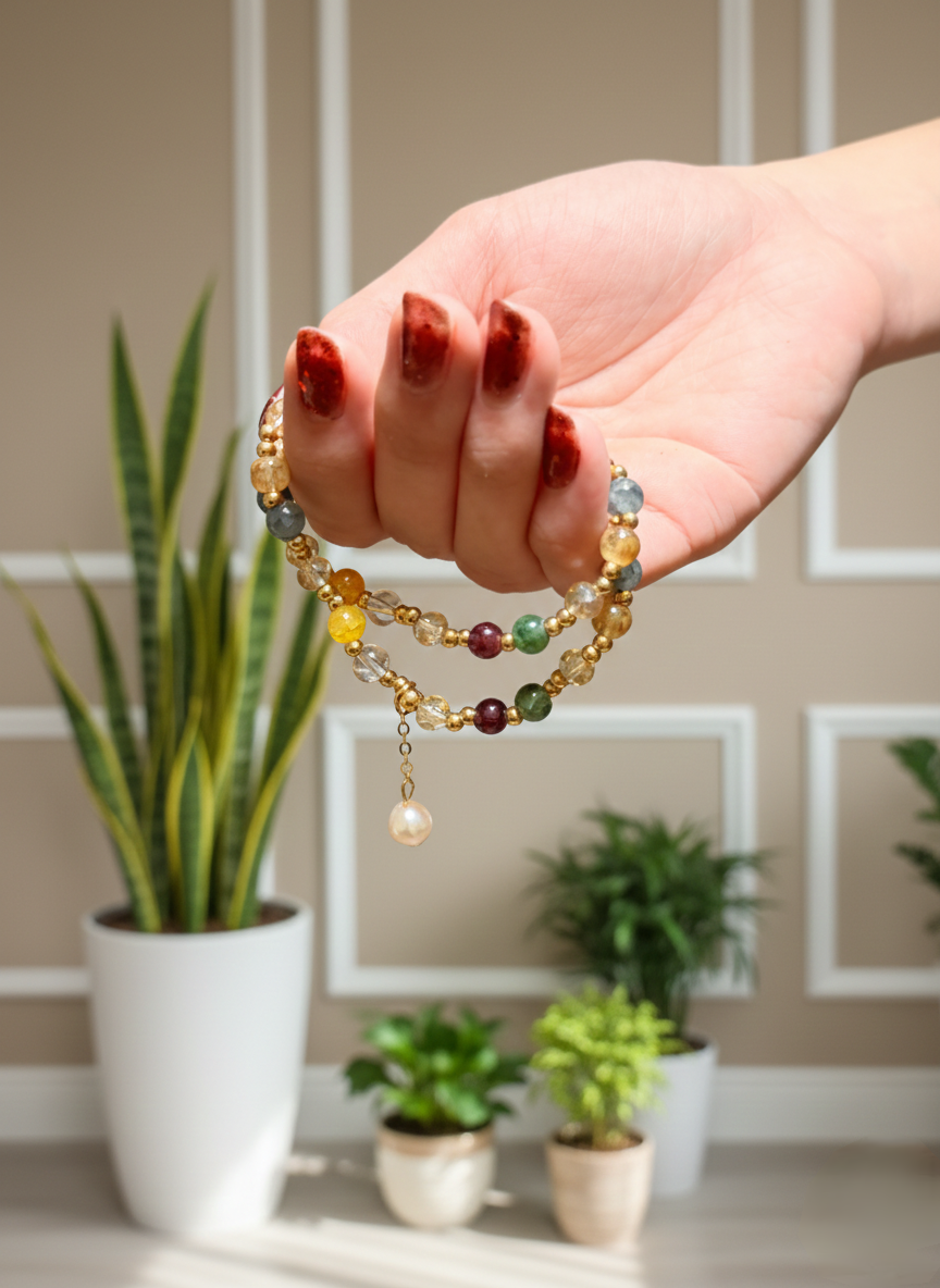 Hand holding a colorful beaded bracelet with a plant and framed pictures in the background