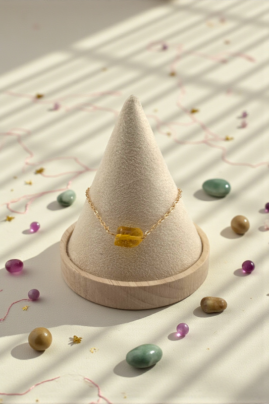 Necklace with a yellow pendant on a cone-shaped wooden stand with small stones around
