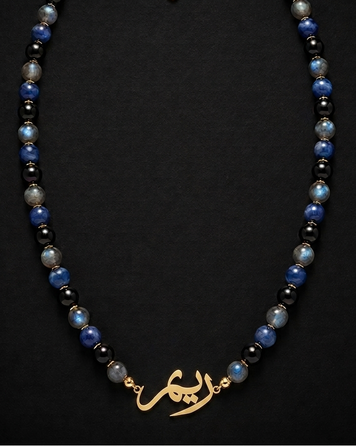 Necklace with blue and black beads and a gold clasp on a black background