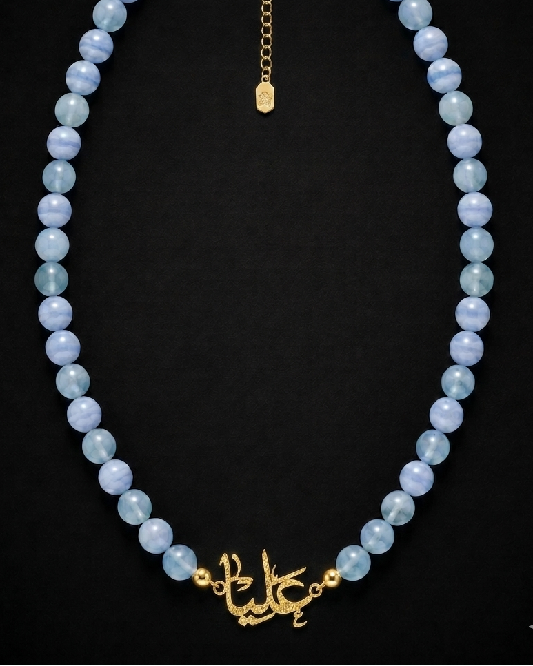 Necklace with blue beads and gold clasp on a black background