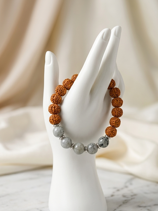 A beaded bracelet displayed on a white hand-shaped stand. The bracelet features textured brown round beads and polished gray marbled round beads, set against a soft beige draped fabric background.