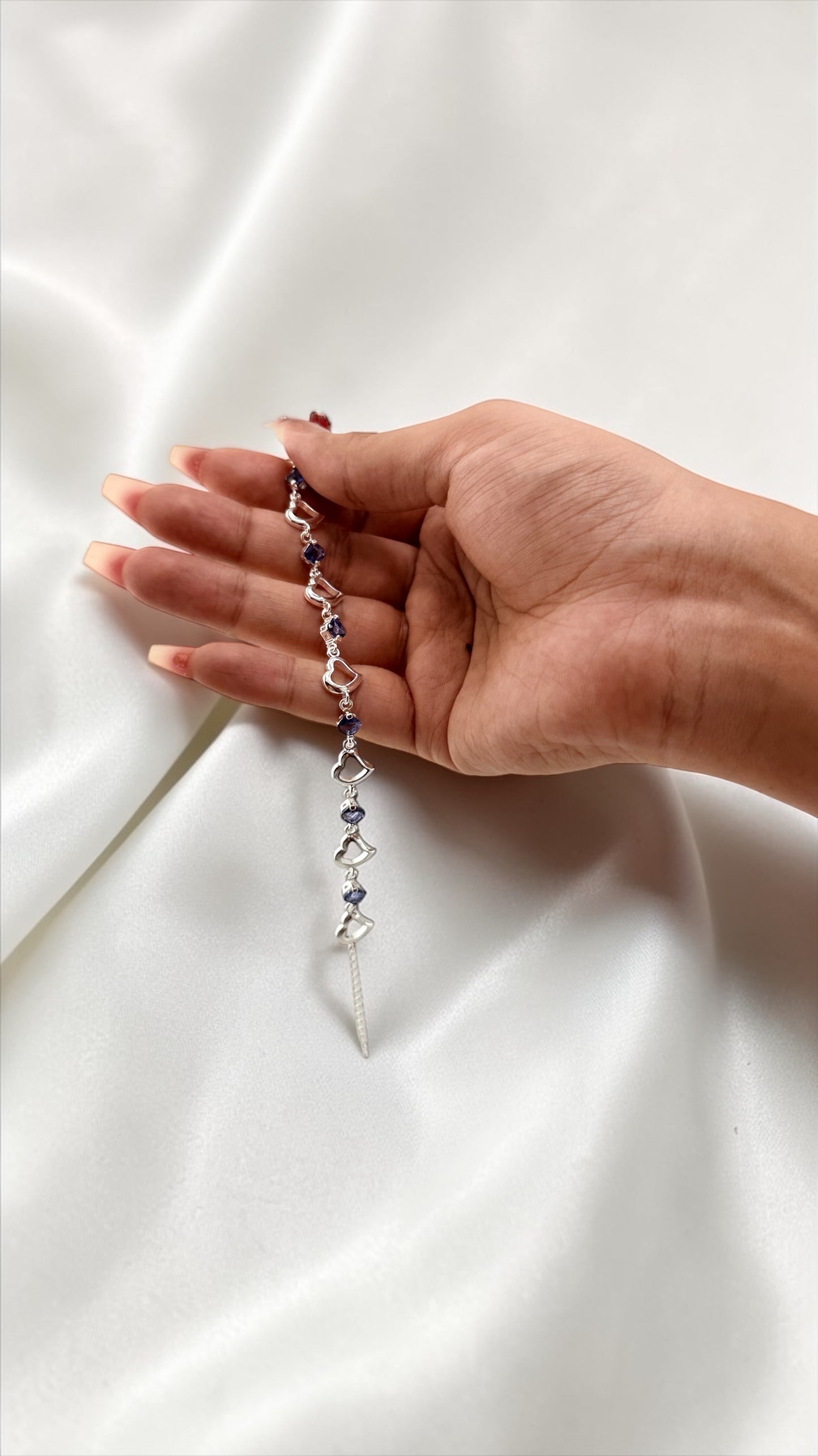 Hand holding a delicate bracelet with a white background