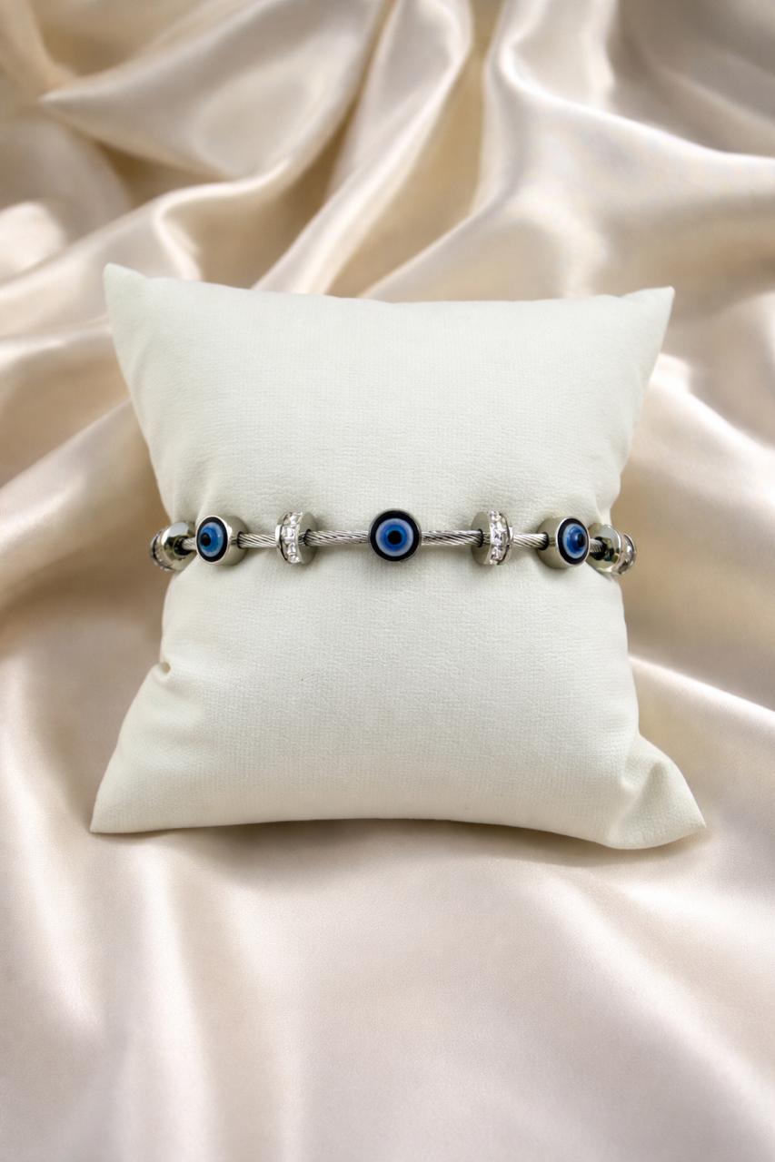 Bracelet with blue beads on a white pillow against a beige fabric background