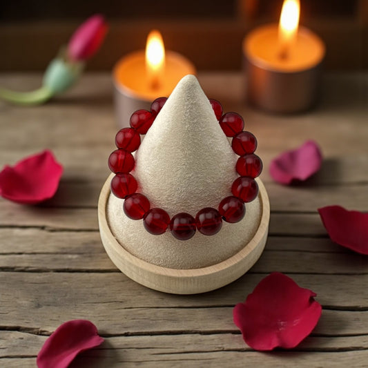 Incense cone with red beads on a wooden surface with candles and rose petals.