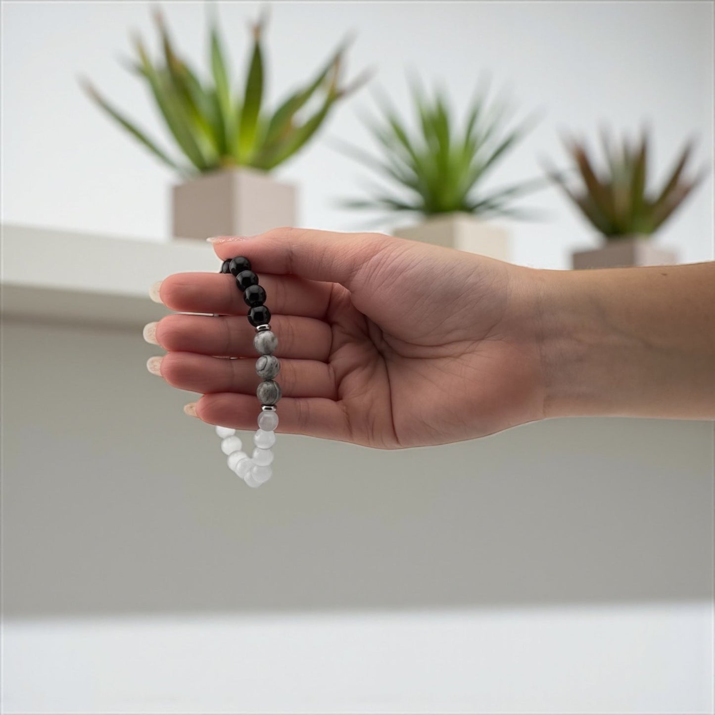 Hand holding a beaded bracelet with a blurred indoor background