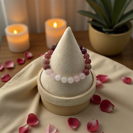 Decorative cone with beads on a wooden stand surrounded by candles and rose petals.