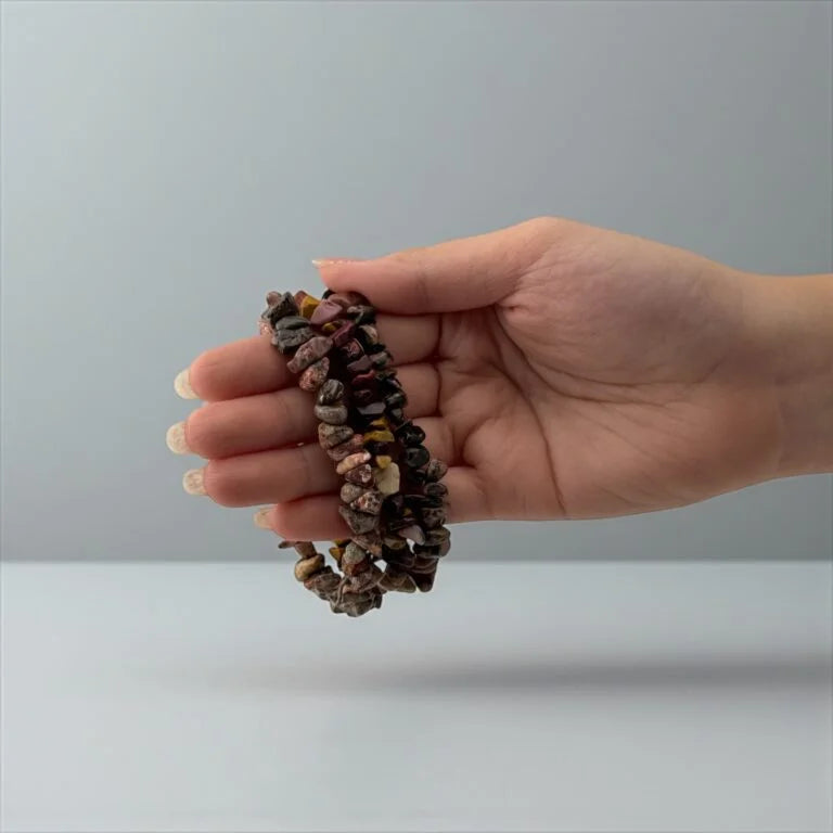 Hand holding a stack of multicolored stones against a plain background