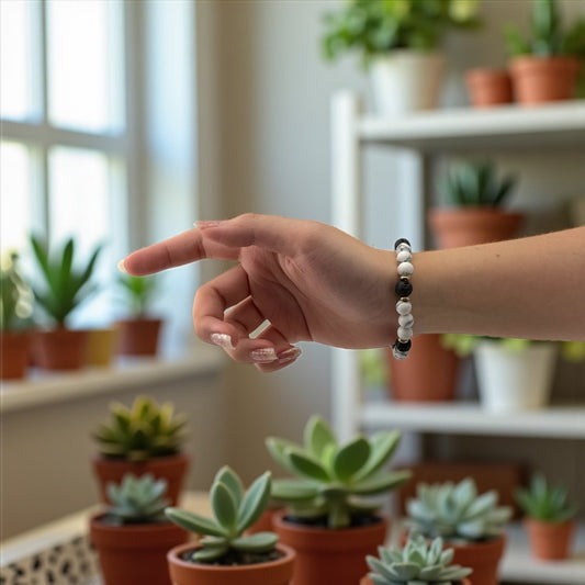 Hand pointing at a collection of potted plants with a blurred indoor setting.