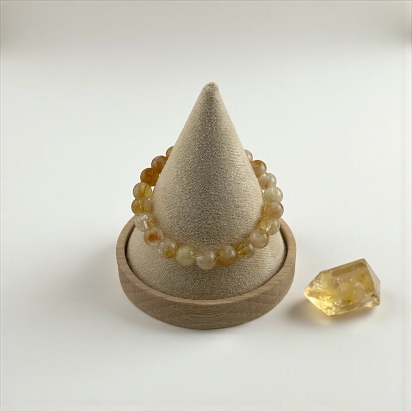 Tapered beige stone with a beaded bracelet on a white background