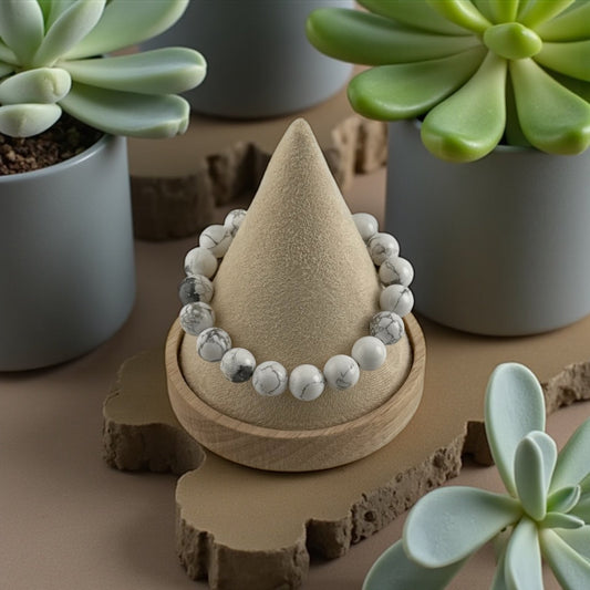 Decorative sand sculpture with beads on a wooden base surrounded by succulent plants.