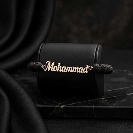 Gold bracelet with 'Mohammad' engraving on a black leather case against a dark background