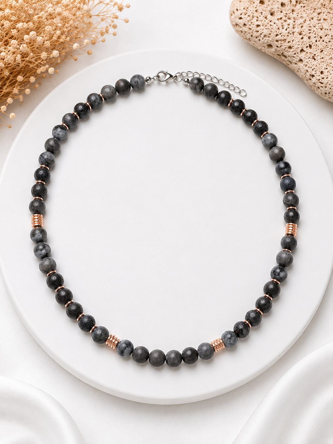 Necklace with black and rose gold beads on a white surface