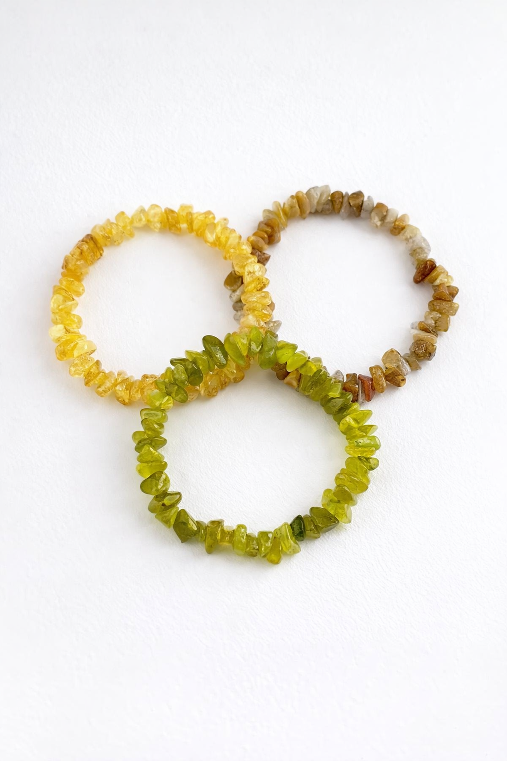 Three beaded bracelets in yellow, green, and brown on a white background