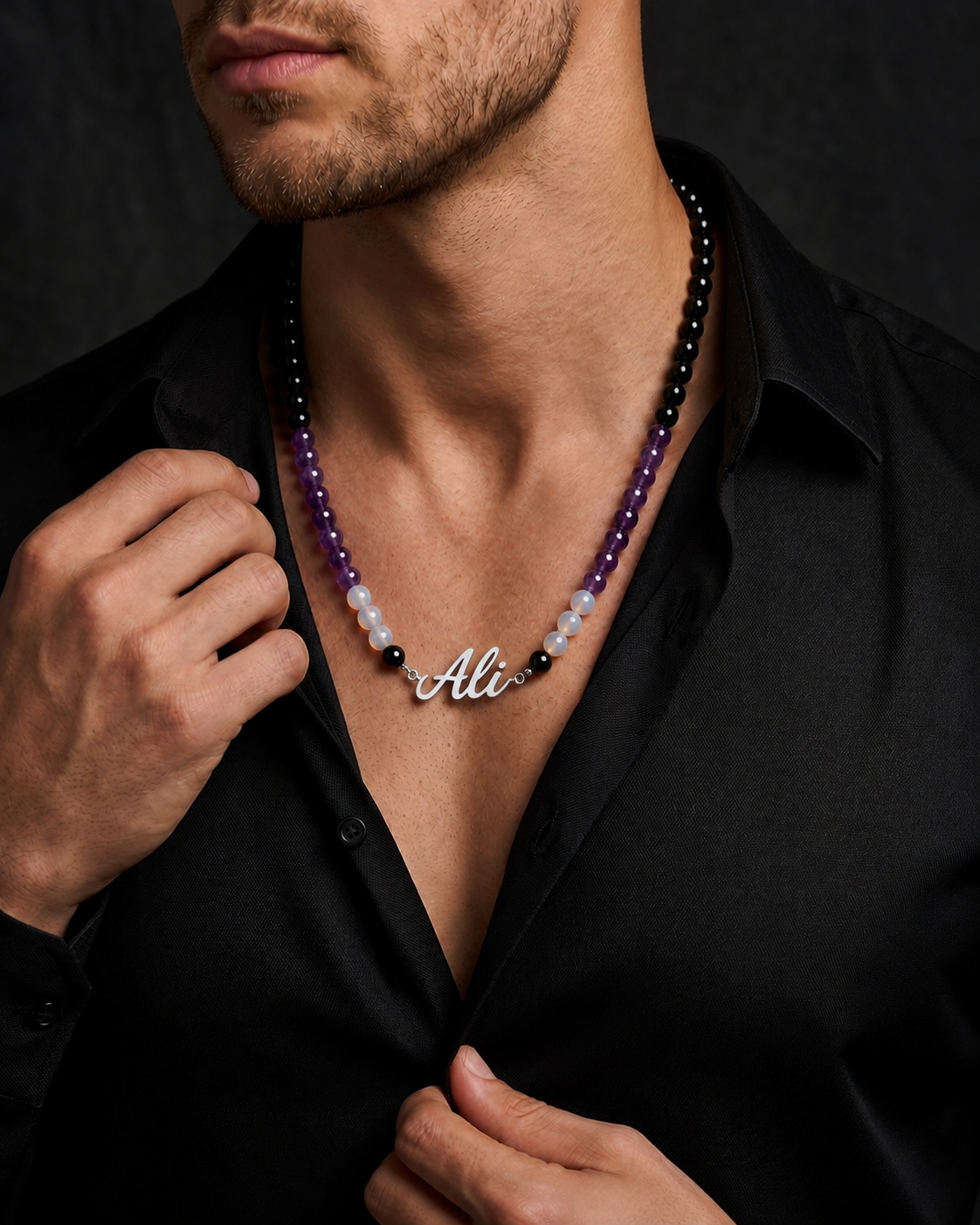 Man wearing a beaded necklace with a name pendant on a black background