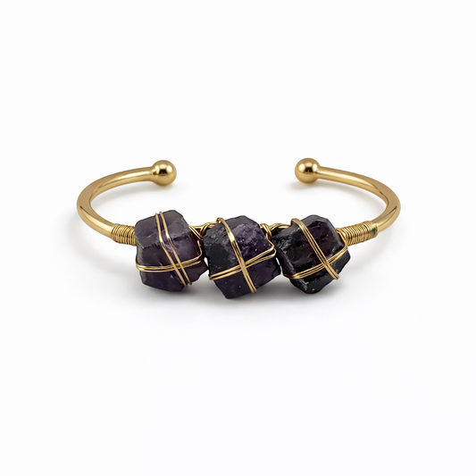 Gold bracelet with purple beads on a white background