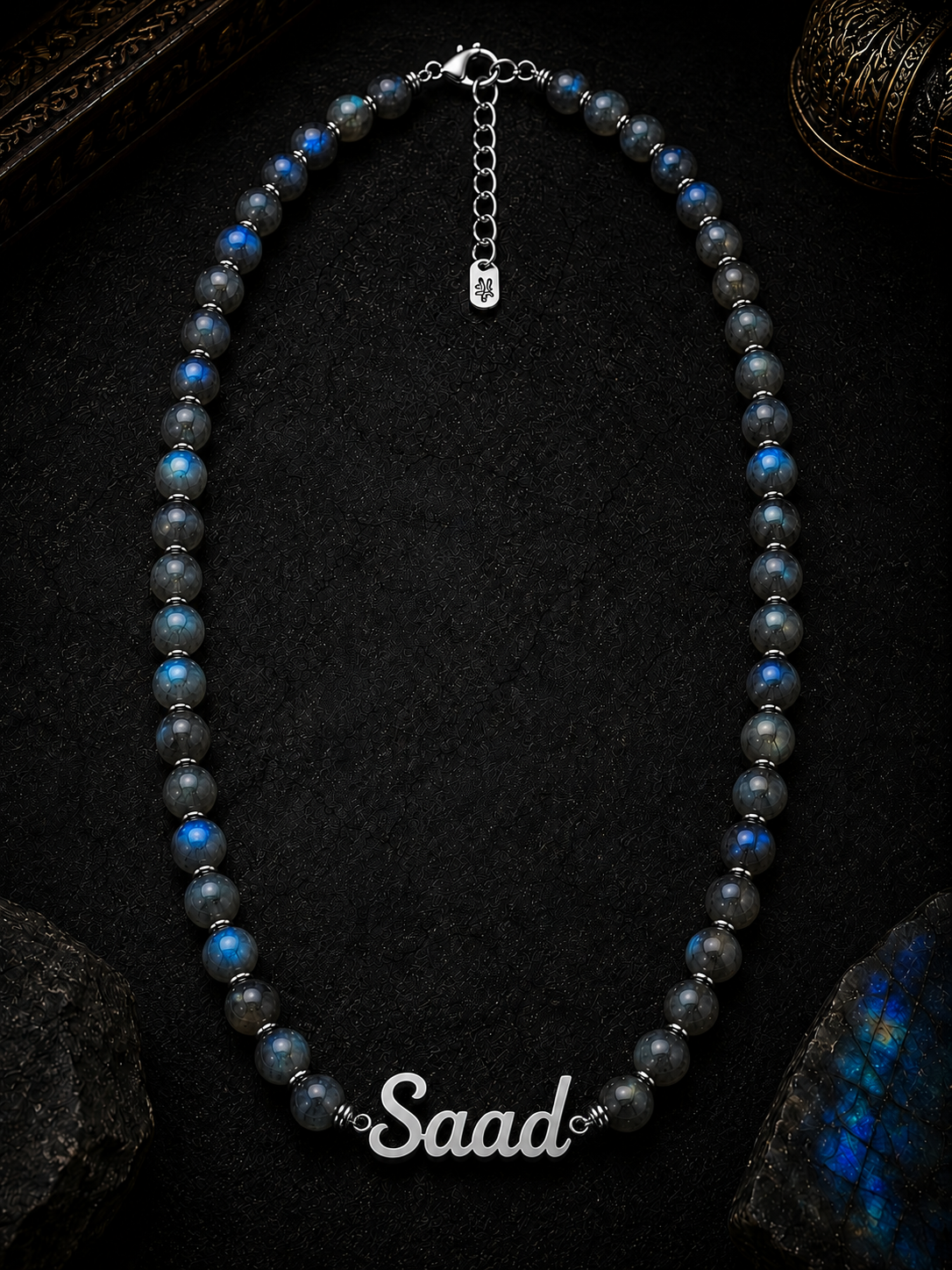 Necklace with blue and black beads and 'Saad' clasp on a dark background