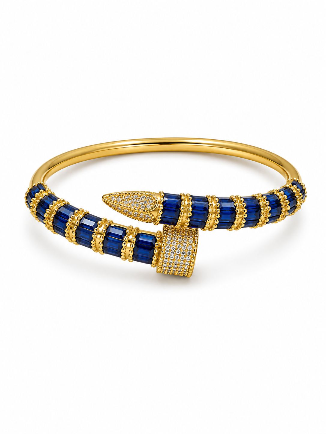 A gold bangle bracelet featuring deep blue rectangular gemstones and pavé-set clear stones, photographed on a clean white background.