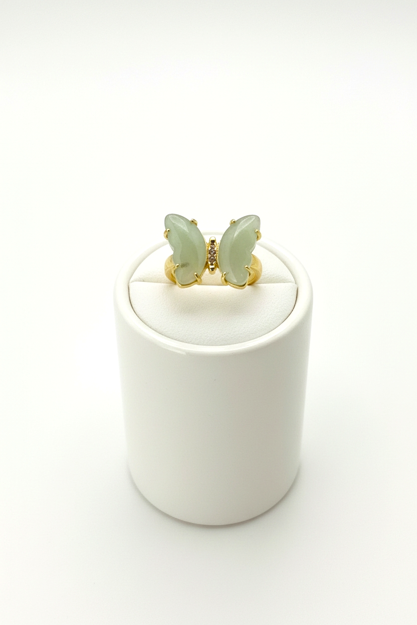 Butterfly-shaped earrings on a white cylindrical stand with a white background