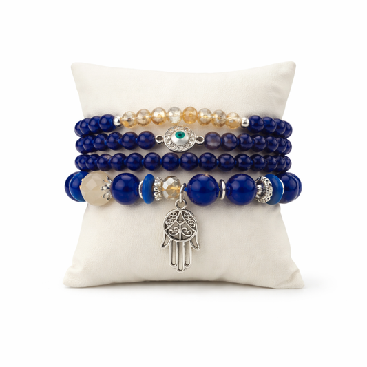 Set of blue beaded bracelets with charms on a white pillow