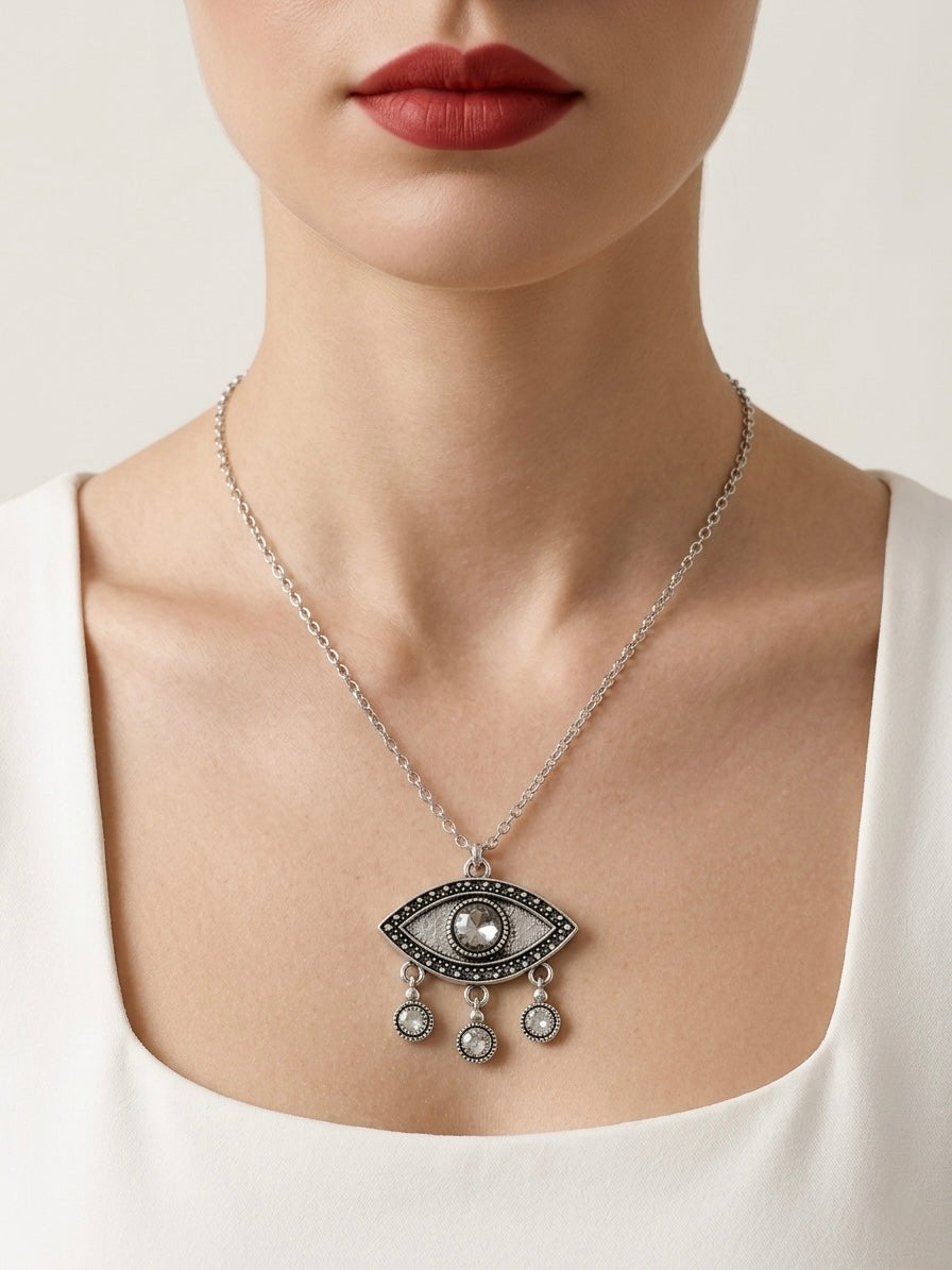 Necklace with eye pendant worn by a person against a neutral background