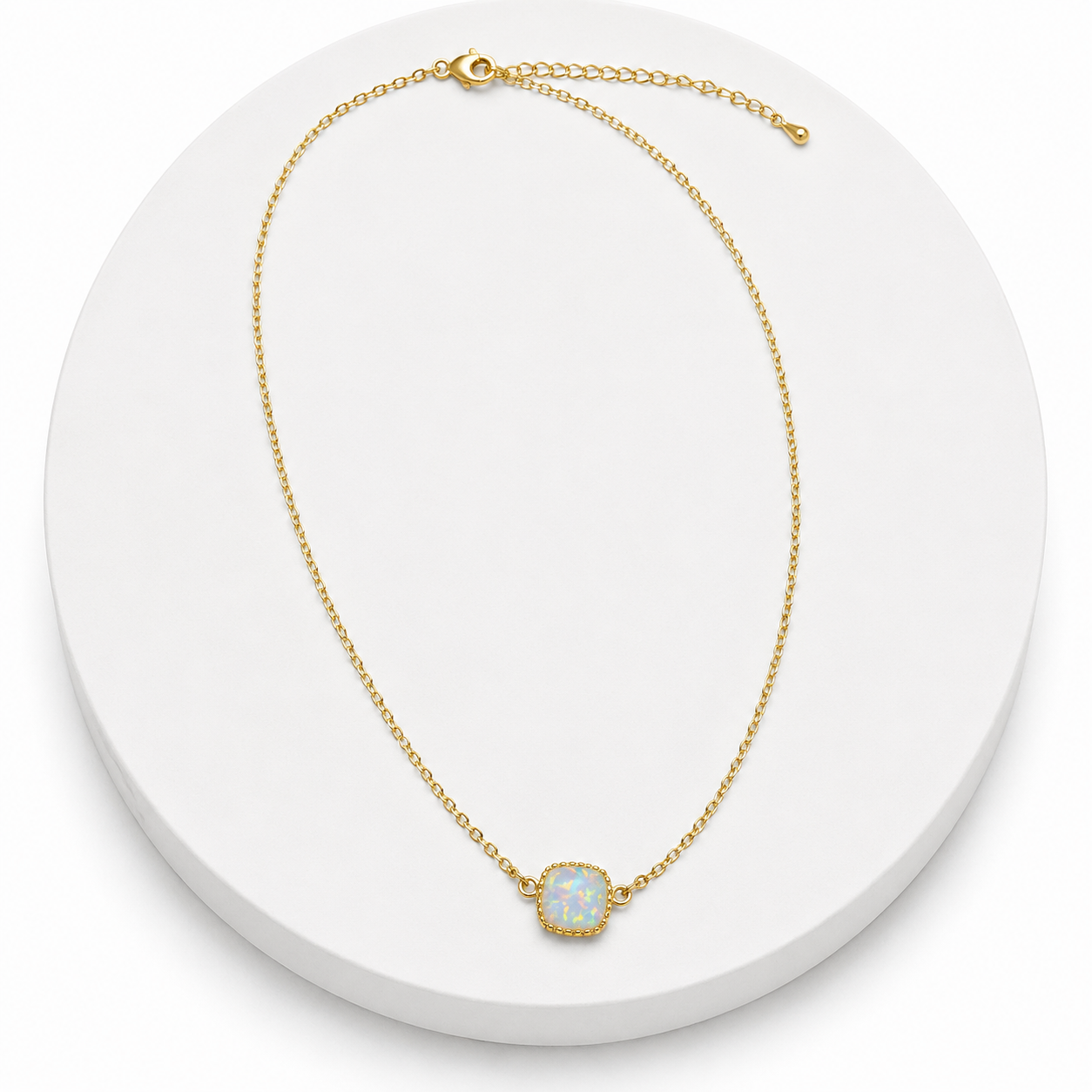 Gold necklace with a small round gemstone on a white background