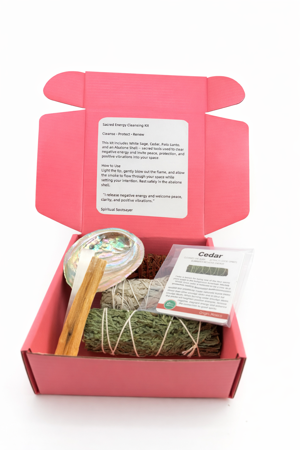 Pink box containing a smudging kit with a crystal, wooden stick, and incense on a white background