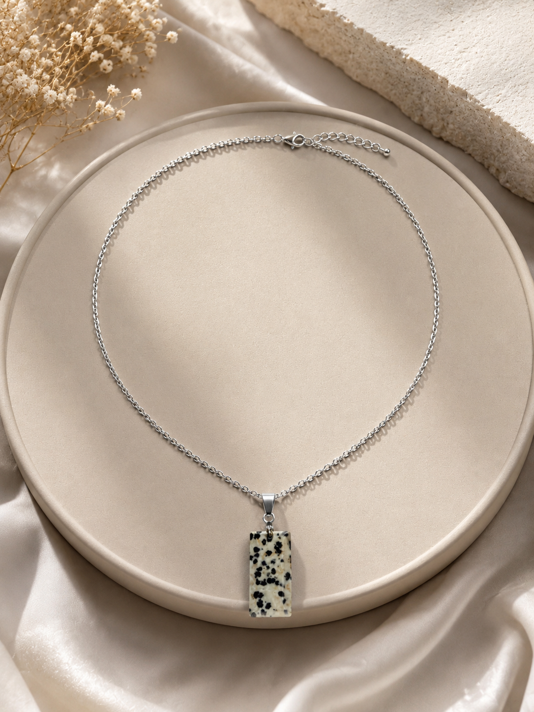 Necklace with a pendant on a beige plate with a soft background